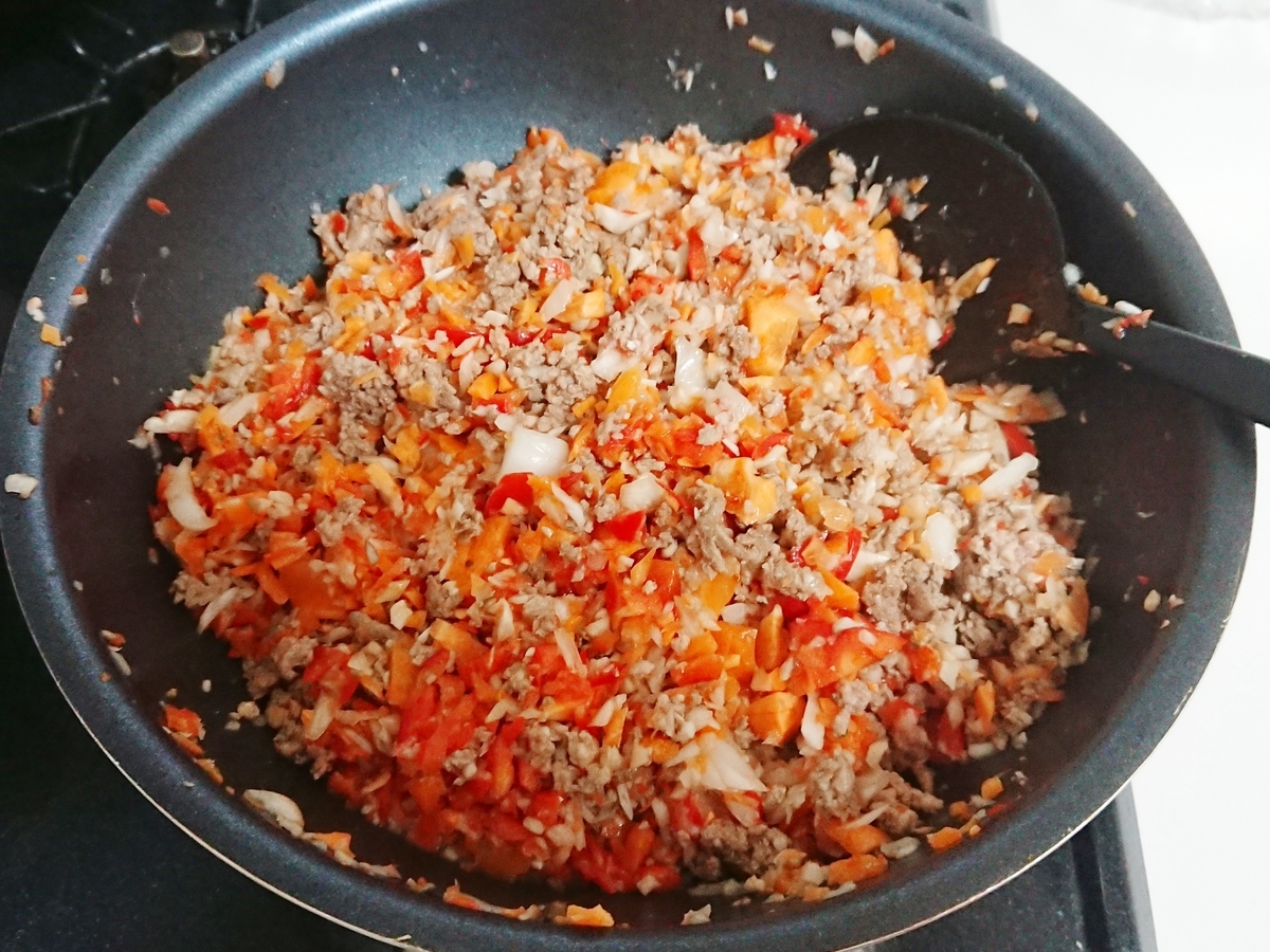 フライパンでひき肉と野菜を炒めている