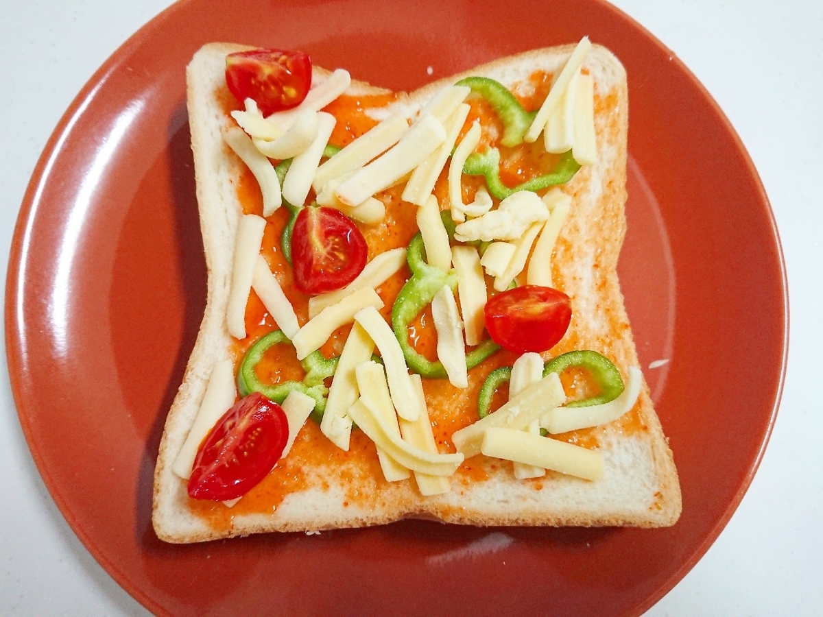 食パンの上にチーズ、トマト、ピーマンがのっている