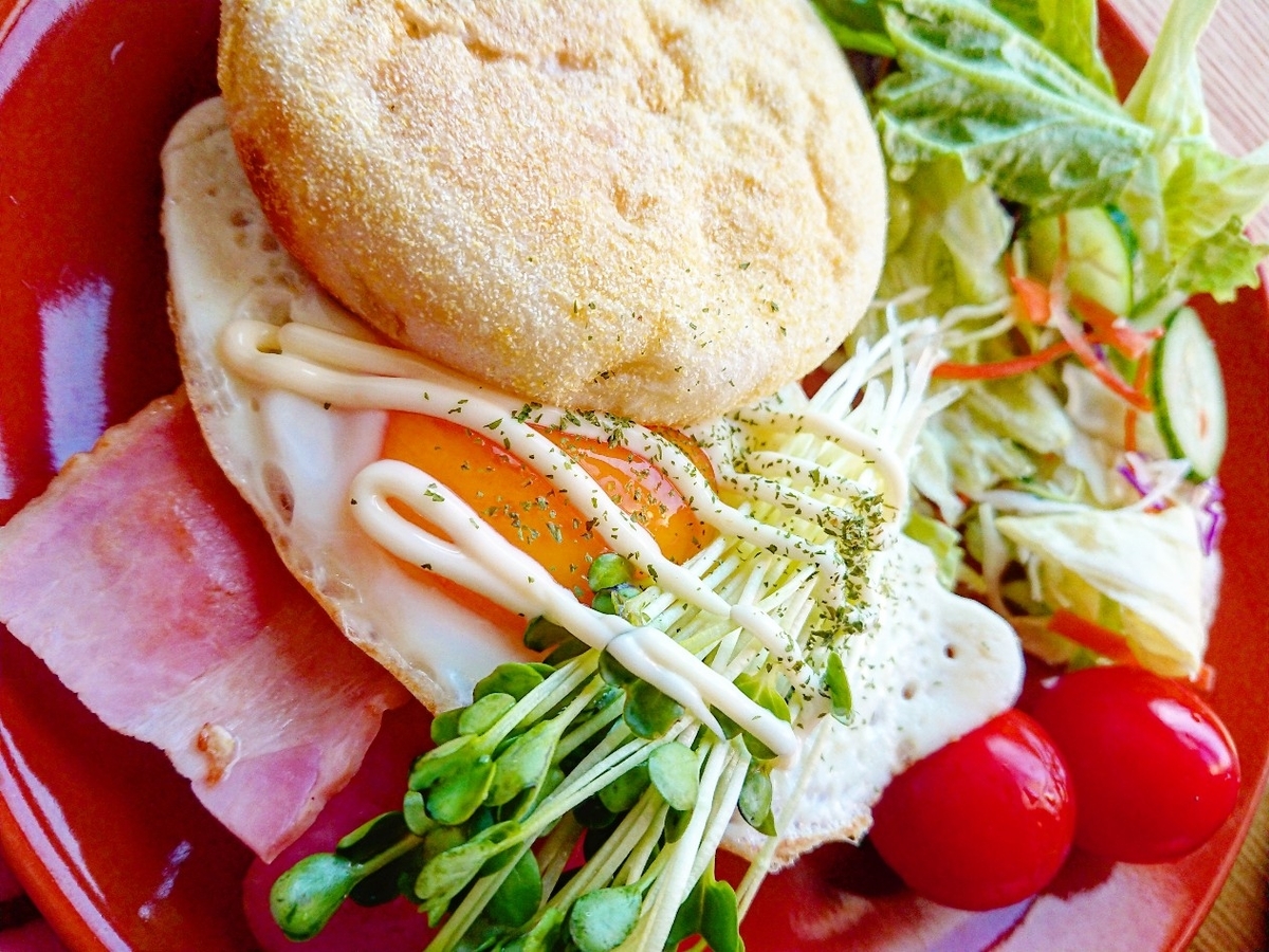 ベーコンと目玉焼きが挟まったマフィンサンド サラダ
