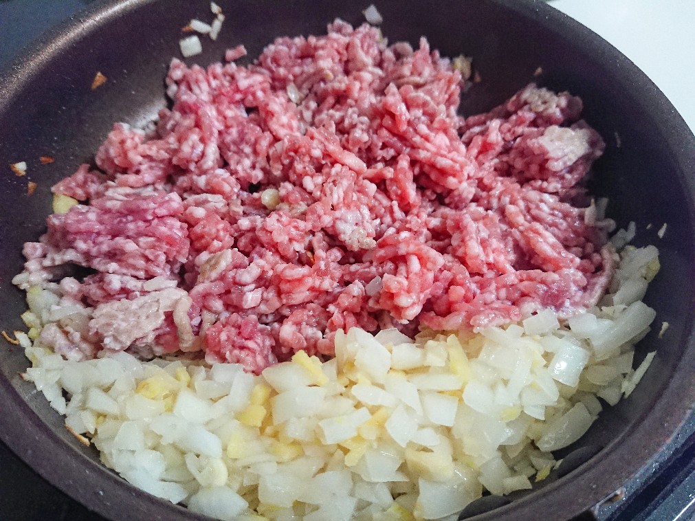 フライパンでミンチ肉とタマネギを炒めている