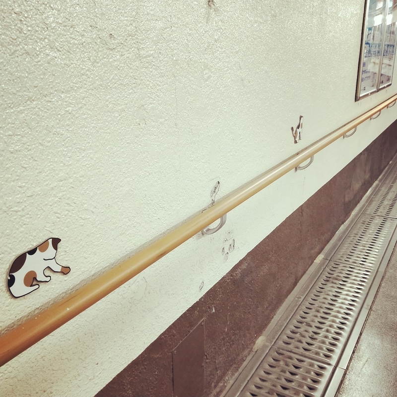 和歌山電鐵の和歌山駅のホームまで続く道に装飾されている別のものに気を取られている猫