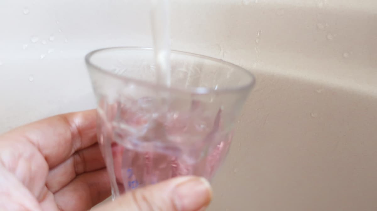 ウォーターチェッカーを入れたグラスに、バスタブ水道水を注いでいるところ
