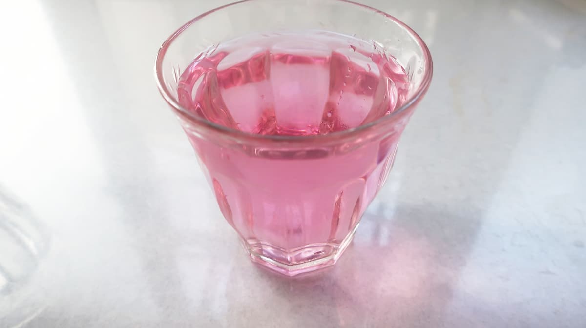 ピンクに染まった水道水が入っているグラス