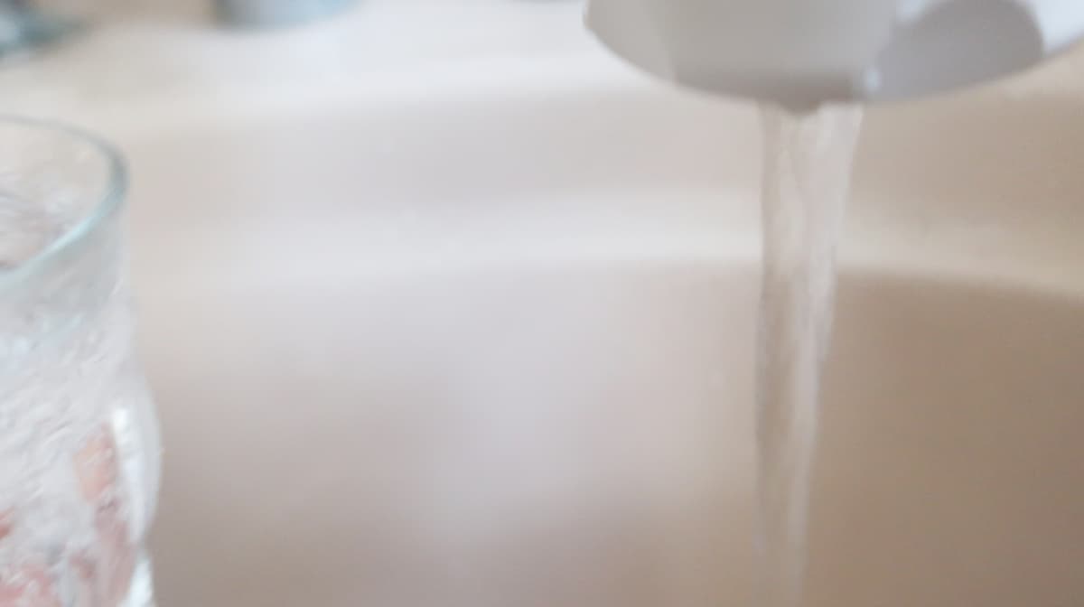 バスタブの蛇口からグラスに水を注いでいるところ