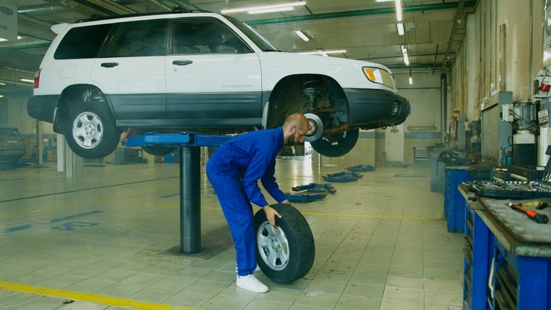 古いドライブシャフトブーツが取り外され、その隣に新品のドライブシャフトブーツが置かれている。車の足回り、露出したドライブシャフトが見える。