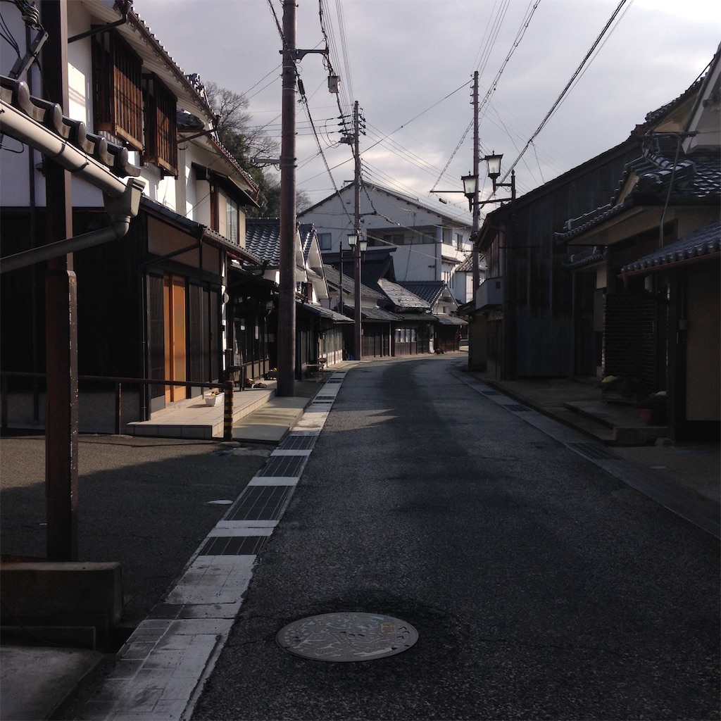 古めのおうちが両脇に並ぶ、車がすれ違えるかどうか程度の道幅の道。