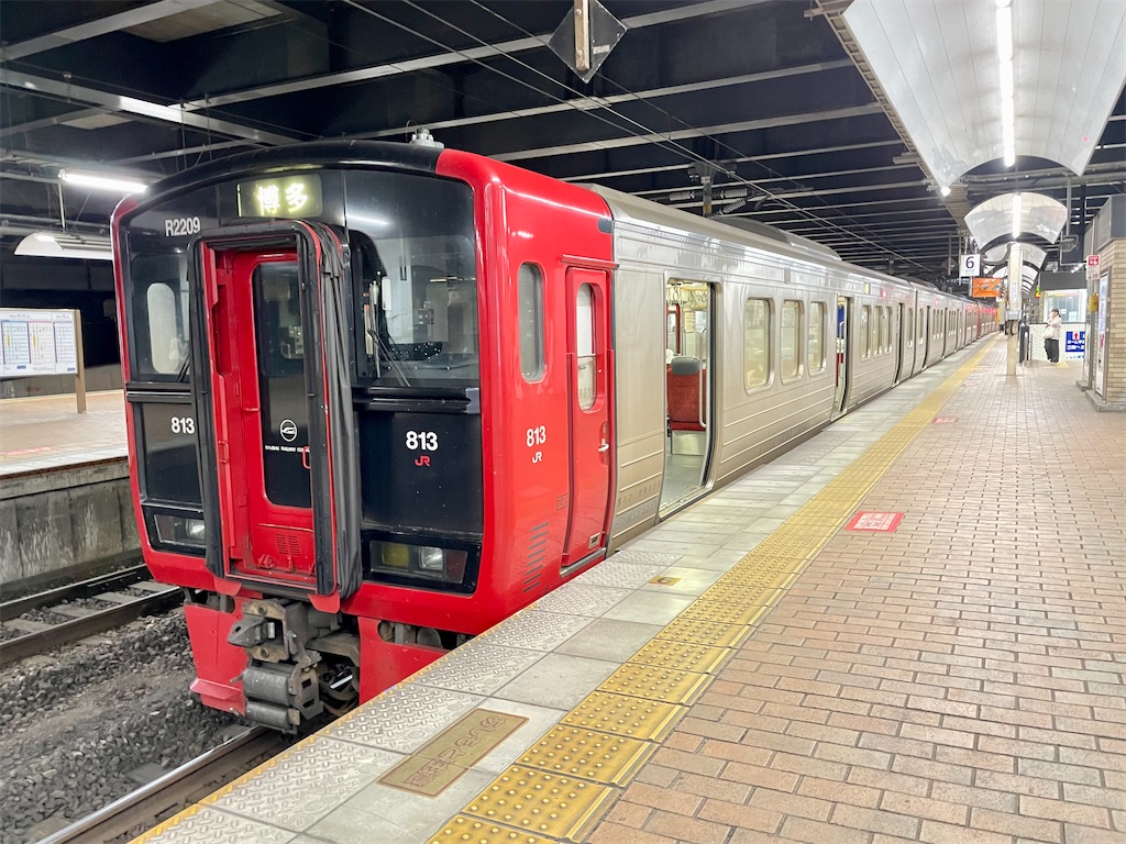 「813」と書かれた電車、博多行き。頭が赤く、車体は全体的に銀色。小倉駅6番線