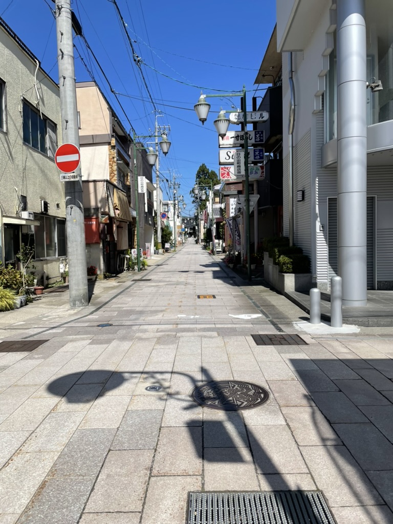 青空、道の写真。両脇に飲み屋さんやご飯屋さんが並んでいる。