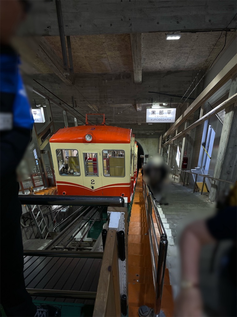 ケーブルカー黒部平駅、降りて階段を上りケーブルカーを見下ろした写真、暗め