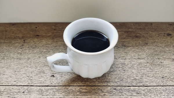 木のテーブルの上に、ぽってりとしたマグカップ。中にはたっぷりと注がれたコーヒー。