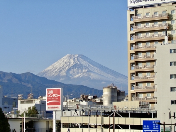 ビルや看板の向こうに冠雪した富士山が見える