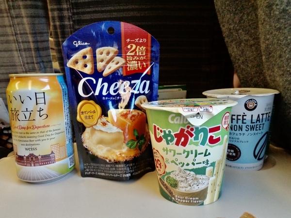 新幹線の指定席のテーブルにビールやコーヒー、じゃがりこなどが置いてある