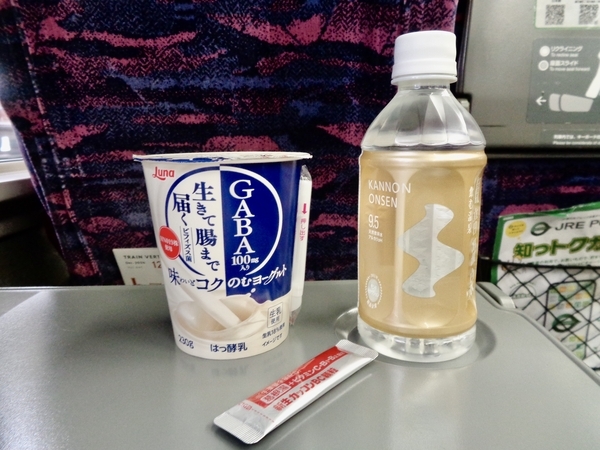新幹線の指定席のテーブルにヨーグルト、水、葛根湯が置いてある