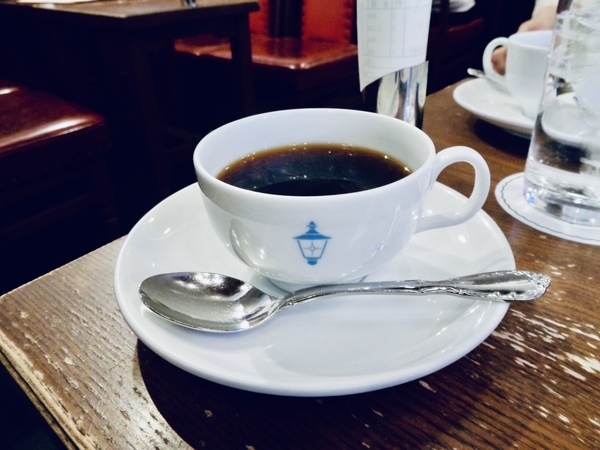 十番館の照明のマークがついた白いコーヒーカップにコーヒーがなみなみ注がれている