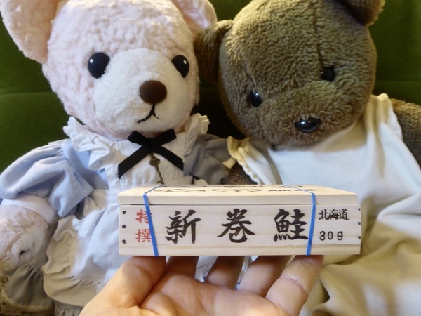 ミニチュア鮭箱を捧げられるテディベア二方の写真
