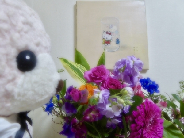 くまのぬいぐるみの写真。花の香りをかいでいる。