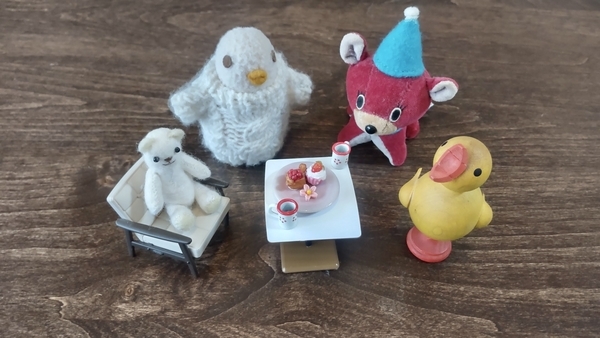 ミニチュアの家具と小さなぬいぐるみ、木彫りの鳥の写真