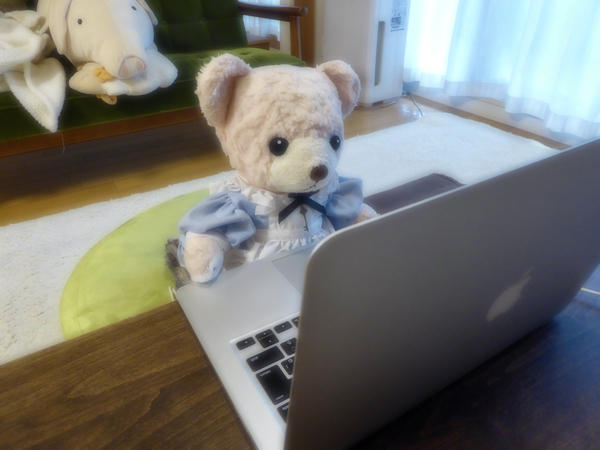 PC の前に座っているくまのぬいぐるみの写真。
