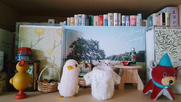 小さなぬいぐるみや木彫りの鳥の写真。白い小さな鳥が脱いだセーターも写っている。