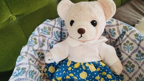 ぬいぐるみの写真。ワンピースを着たくまがくつろいでいる。