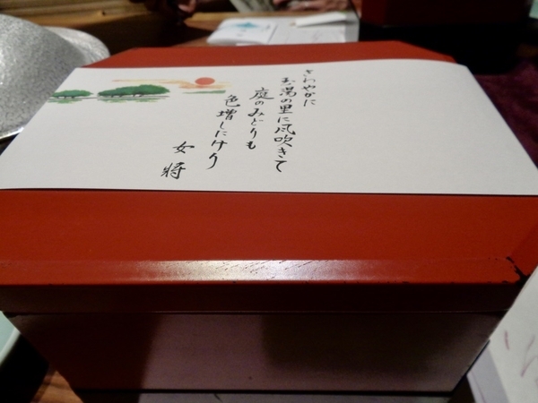 前菜のお重の写真。女将の短歌が紙に書いてあって、それで封をしている。