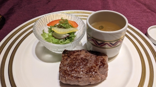 ステーキの写真。スープとサラダが添えてある。
