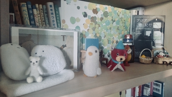 本棚の一画を撮った写真。ちいさなぬいぐるみや木彫りの鳥が暮らしている。