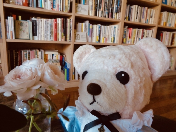 花とぬいぐるみの写真。ガラスの器に活けたバラとくま。