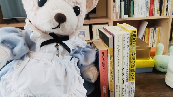 本とぬいぐるみの写真。五冊の本とエプロンドレスを着たくま。