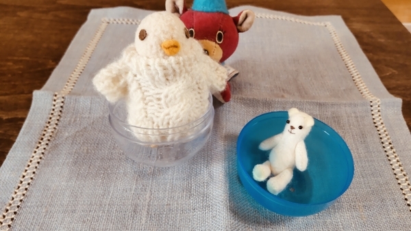 小さなぬいぐるみの写真。鳥やくまが、おもちゃの入っていたカプセルに入って遊んでいる。