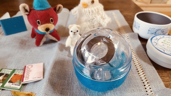 小さなぬいぐるみとトイカプセルの写真。カプセルのなかに、ミニチュアの何かが入っている。