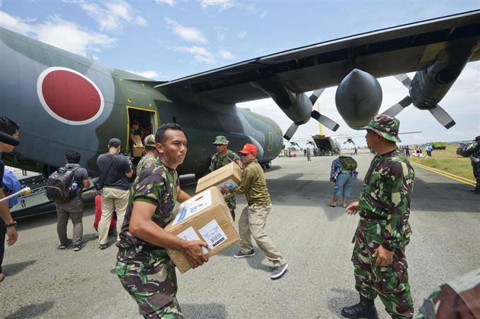 　パルの空港に到着した航空自衛隊のＣ１３０輸送機から救援物資を運び出す隊員とインドネシア軍の関係者ら＝６日、インドネシア・スラウェシ島（共同）