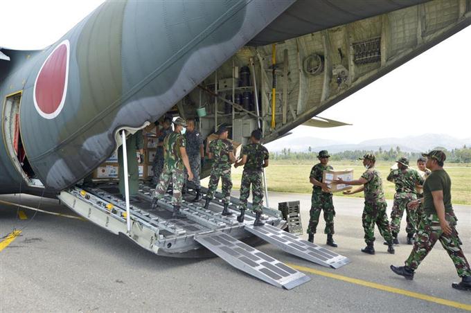 　パルの空港に到着した航空自衛隊のＣ１３０輸送機から救援物資を運び出す隊員とインドネシア軍の関係者ら＝６日、インドネシア・スラウェシ島（共同）