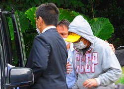 米軍機へのレーザー照射で威力業務妨害の疑いで同行される容疑者(右)=7日午前10時25分、宜野湾市大山