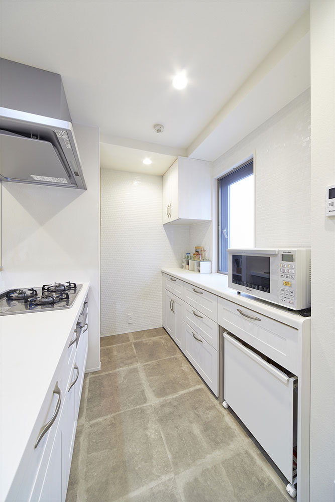 システムキッチンとカウンターの高さを揃えた背面のカウンター収納の写真