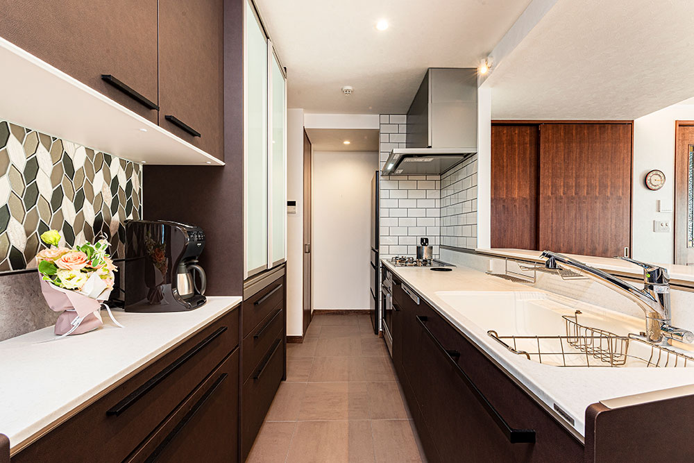 茶系の扉で統一したシステムキッチンと背面収納の写真