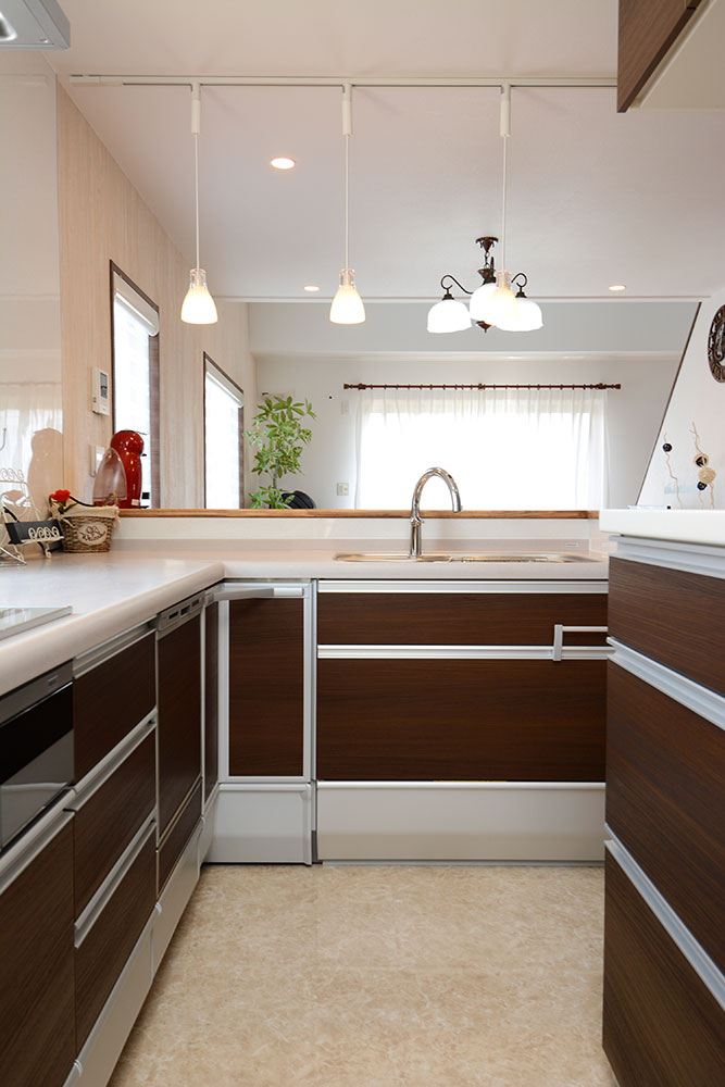 シンク側はダイニング方向を向き、コンロ側はやや奥まった壁付けに配置したL型キッチンの写真