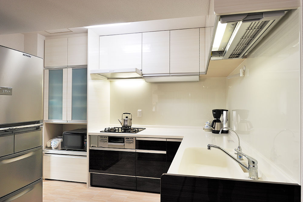 白と黒の対比が美しいL型キッチンの写真