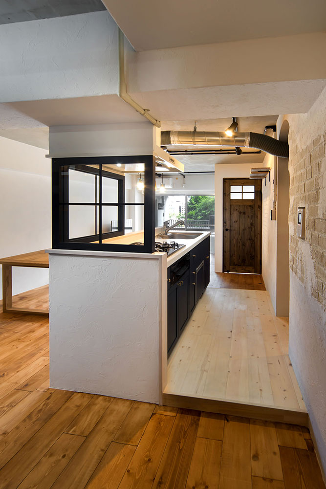 ガラスの建具やグラス型のペンダントライトを採用し、圧迫感のない設計にしたアイランドキッチンの写真