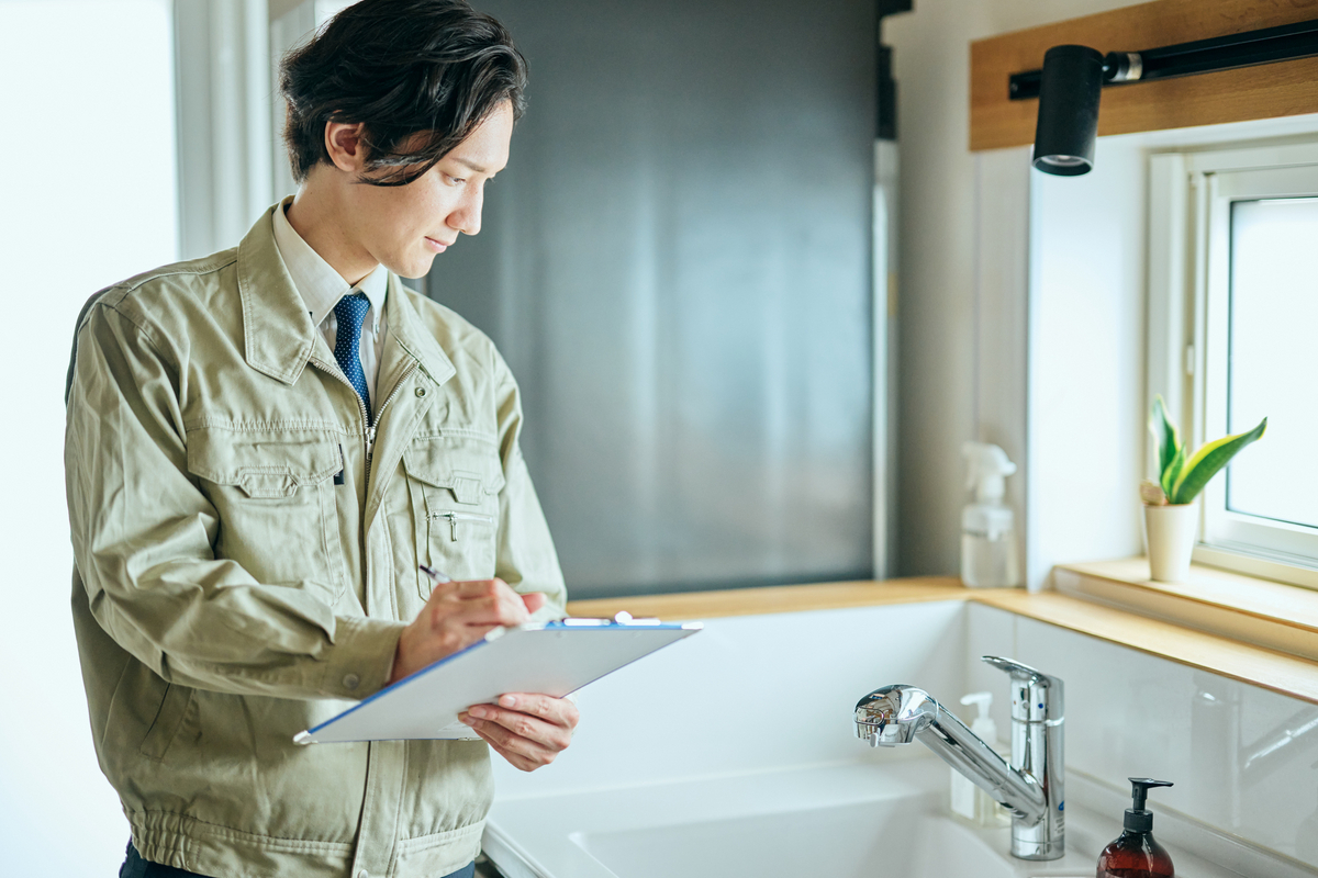 水回りの設備をチェックしているリフォーム会社の担当者のイメージ