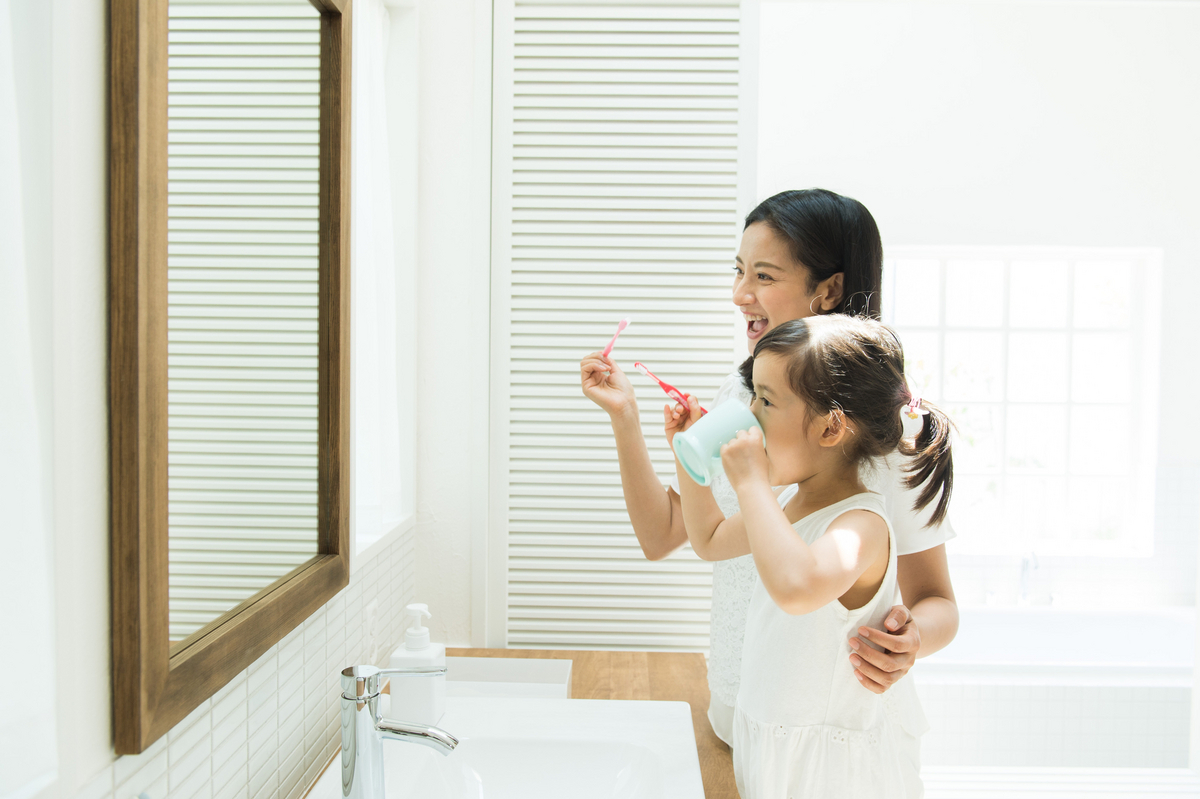 洗面台の前に親子で並んで歯磨きしている様子