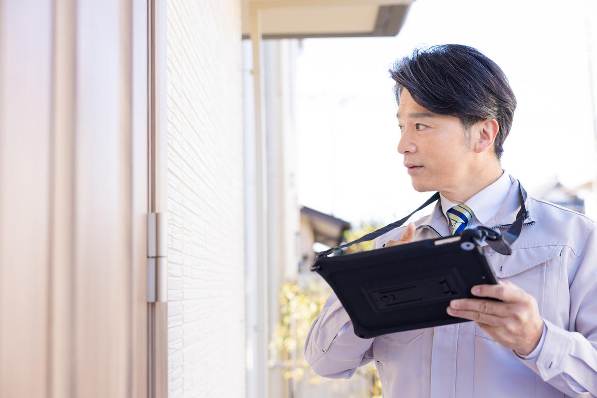 玄関ドアを点検する男性のイメージ