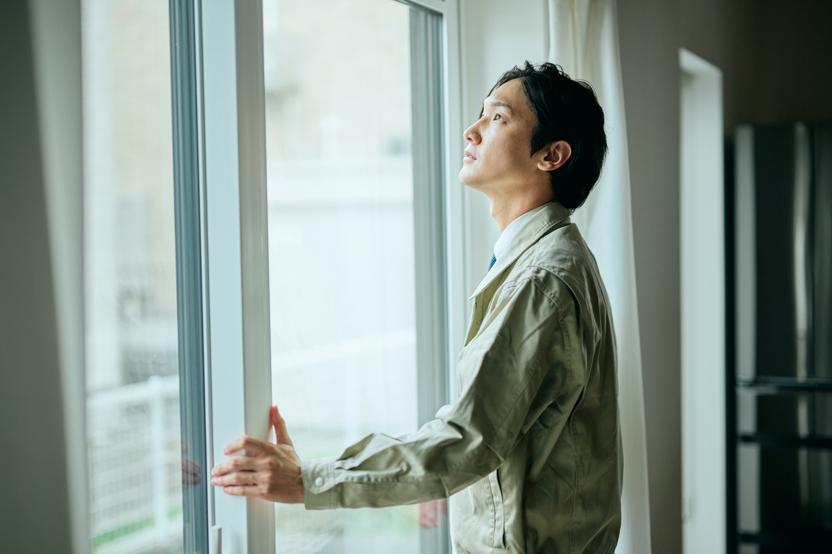窓をチェックする作業服の男性のイメージ