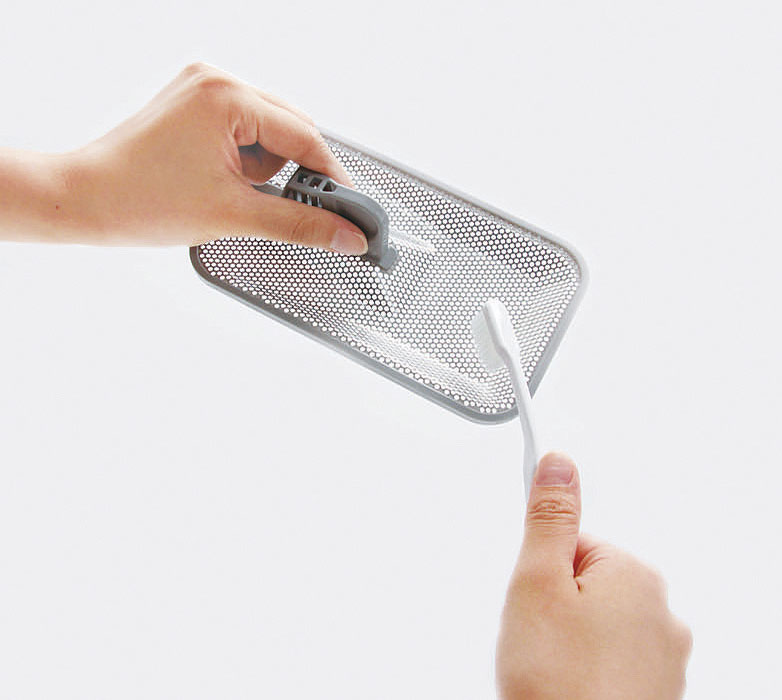 食洗機の残さいフィルターについた汚れをブラシでこする様子