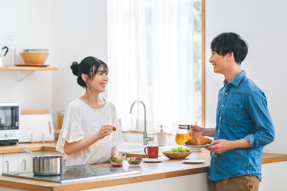 キッチンを挟んで会話している夫婦のイメージ