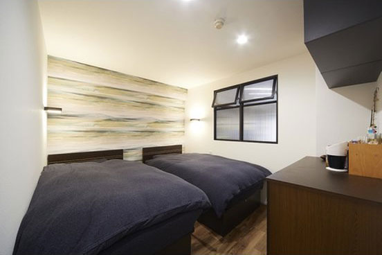 寝室のベッドヘッド部にはシックな柄のデザインクロス