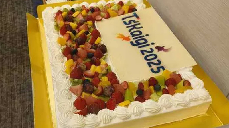 TskaiGi2025のロゴが入ったフルーツたっぷりの大型ケーキ。鮮やかなフルーツとホイップクリームが印象的