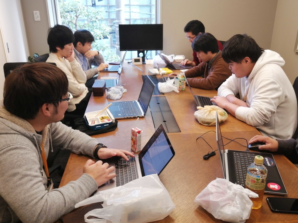 会議室に昼ごはんおPCを持ち寄り発表を聞いている