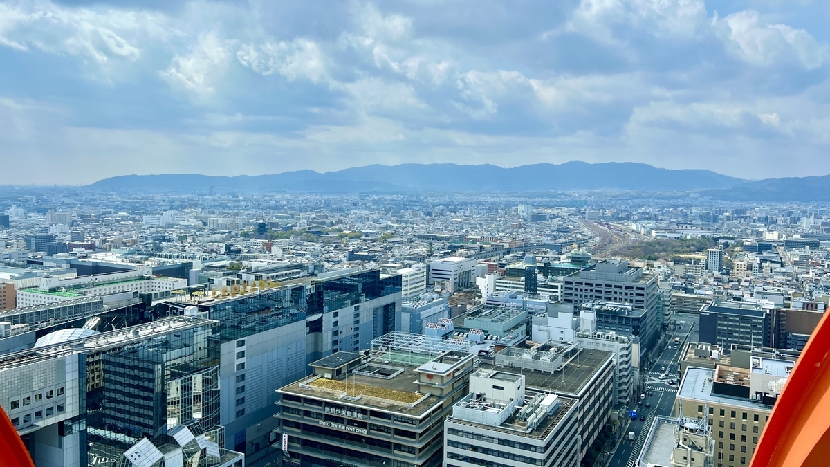 青空の下に広がる京都駅周辺のビル群と山並みを一望する景色