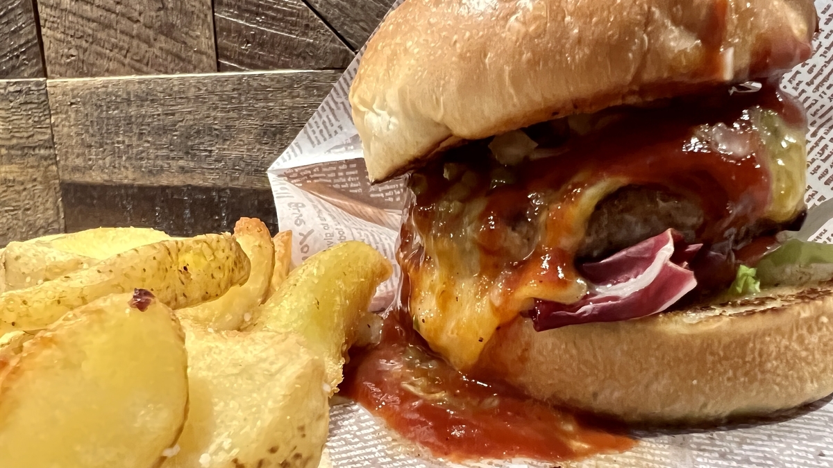 とろけるチーズとソースがたっぷりかかった熟成牛チーズバーガーとポテトチップス